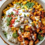 Street Corn Chicken Rice Bowl on a slate tray, garnished with cilantro and lime wedges, with a fork resting nearby